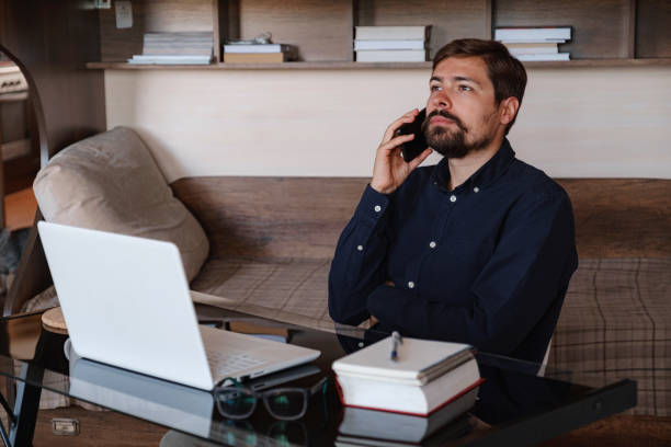 istock Handsome young man working on laptop. Businessman using phone. 1298121740