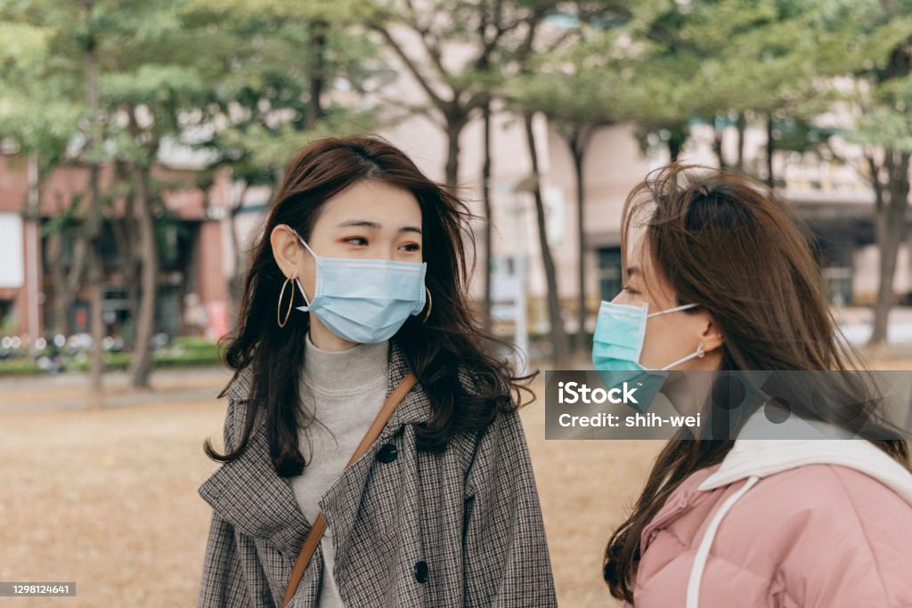 Chatting with female friends outdoors Protective Face Mask Stock Photo