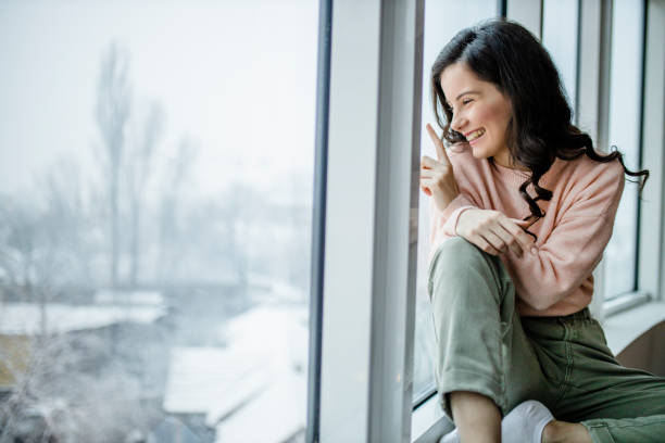istock Beautiful young smiling woman looking outside window 1298127055