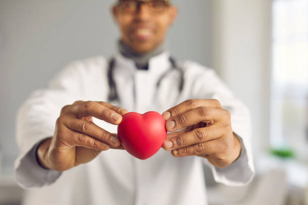 Doctor holding red heart and promoting healthy lifestyle and prevention of heart diseases stock photo