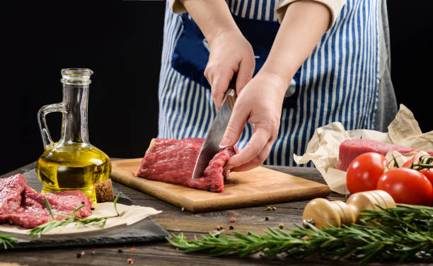 istock A woman cuts a piece of beef into steaks. 1298132357