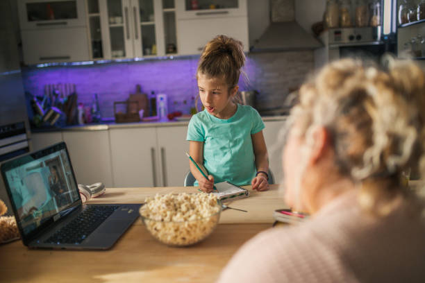 little child girl with grandmother using laptop at home - eating senior adult color image spaghetti imagens e fotografias de stock