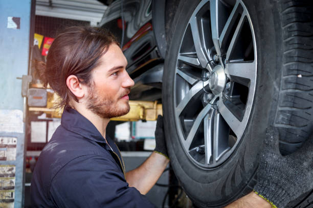 istock Auto mechanic working in garage, checking wheels, car service technician repairing customer car at automobile service center, inspecting car under body and suspension system, vehicle repair service shop. 1298135308