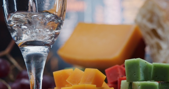 Pouring wine with multi colored types of hard cheese. Close-up front view