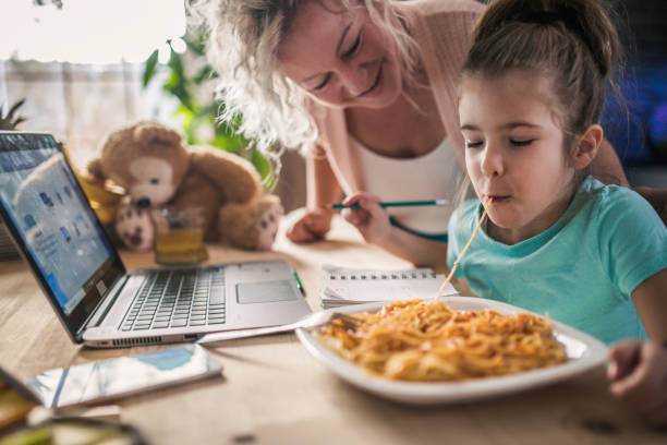 petite fille d’enfant avec la grand-mère utilisant l’ordinateur portatif à la maison - eating senior adult color image spaghetti photos et images de collection