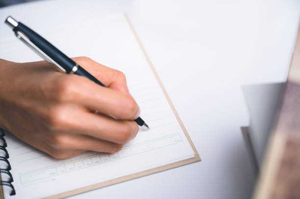 istock People writing on notebook and work with paper on wooden table. 1298136085