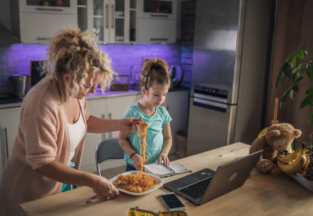 petite fille d’enfant avec la grand-mère utilisant l’ordinateur portatif à la maison - eating senior adult color image spaghetti photos et images de collection