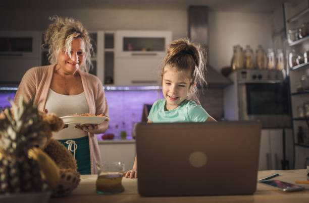 little child girl with grandmother using laptop at home - eating senior adult color image spaghetti imagens e fotografias de stock