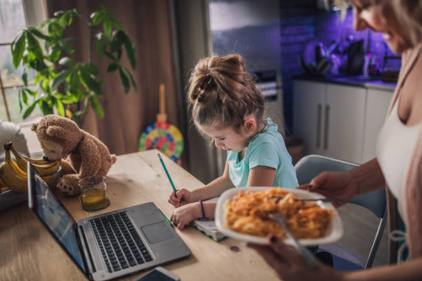 petite fille d’enfant avec la grand-mère utilisant l’ordinateur portatif à la maison - eating senior adult color image spaghetti photos et images de collection