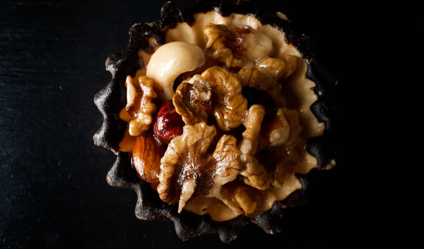 Delicious fresh cake with nuts on a black plate. Close up, top view.