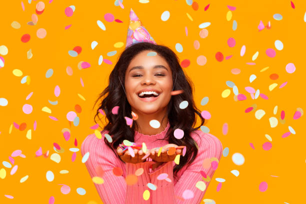 happy birthday! cheerful funny ethnic  woman with festive confetti on yellow - birthday party adult women imagens e fotografias de stock