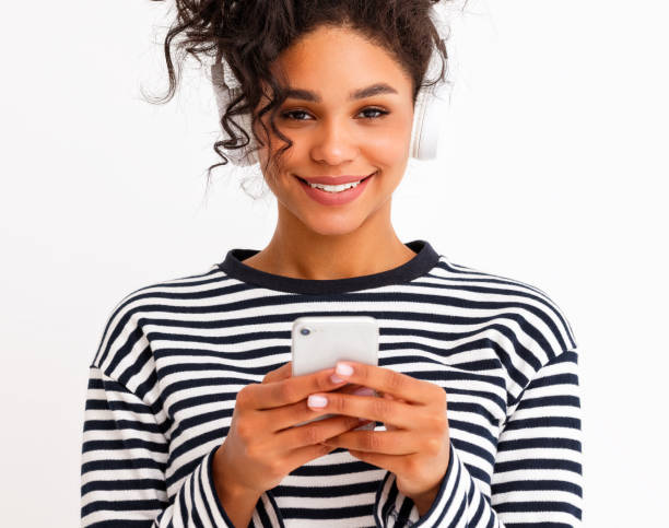 istock Cheerful ethnic female in headphones using smartphone 1298137952