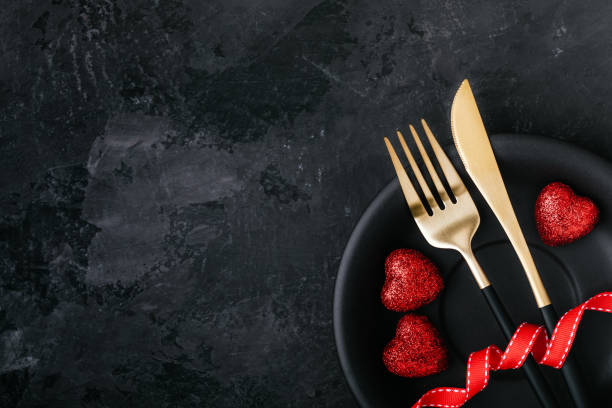 istock Valentine's Day table setting with plate, gold knife, fork, red ribbon and hearts 1298140315
