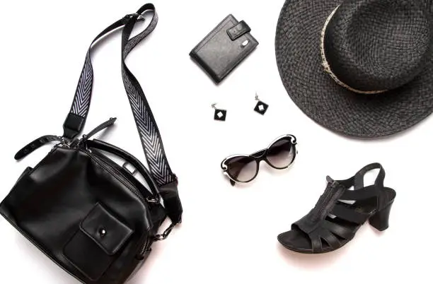 Flat lay female clothes and accessories collage, black womenâs hat, glasses, earring, shoes and cardholder isolated on white background. Upper view.