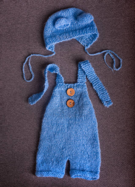 istock Knitted jumpsuit with a hat for a newborn on a gray background. 1298140741