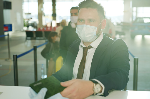 Businessman in mask going to business trip he standing at reception and check-in