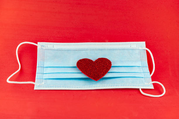 istock Face mask with a heart on red background 1298144901