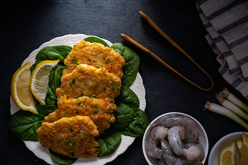 Shrimp and scallion jeon - Korean savory pancake - garnished with chopped chives and lemon wedges.\n\nThe pancakes are quick and easy to make. Nearly any type of meat, seafood, and vegetables is chopped or thinly sliced, then combined with a batter made with flour, potato starch, and water. Finish with a brief fry on a griddle or skillet. It's a great way to recycle leftovers.