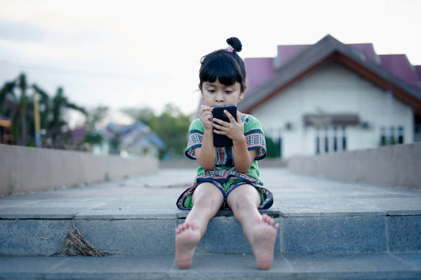 Cute little girl using smart phone at public park