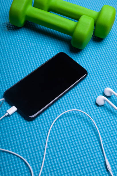 istock two green dummbells with smartphone with blank screen and headphones 1298151457