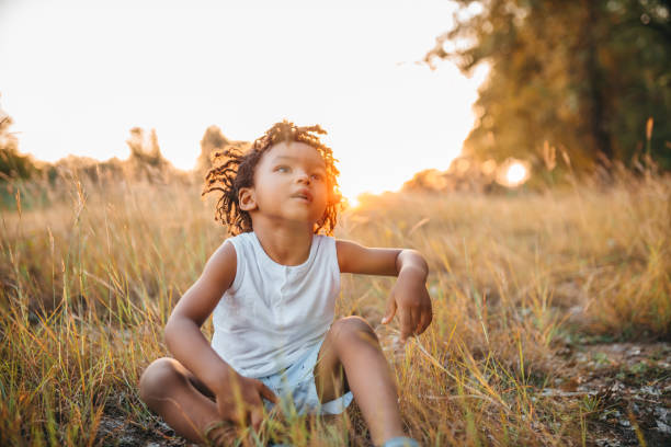 istock The little boy is sitting in the grass 1298151534