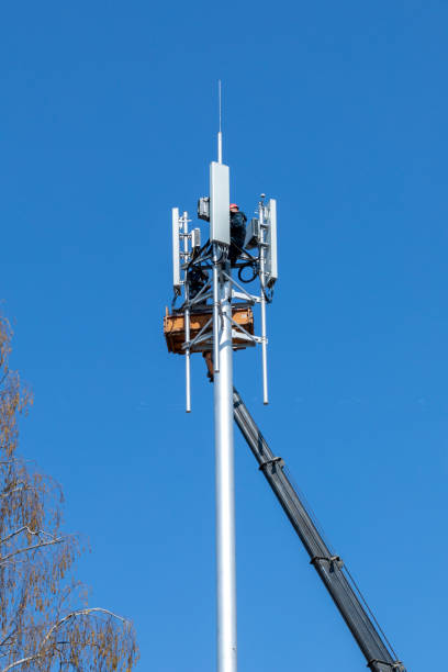 istock Crane with telescopic boom lift used as an aerial working platform. Worker install cellular base station with transmitters 3G, 4G, 5G and antennas on cell tower on blue sky background. 1298159313