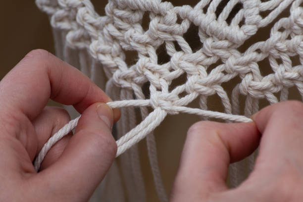 Weaving macrame Half finished macrame. Close up shot of the hand of a girl weaving macrame. Home hobby for home decorations. macrame photos stock pictures, royalty-free photos & images