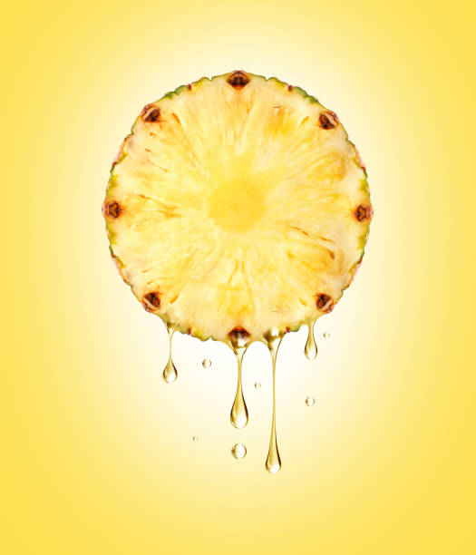 istock Drops of juice dripping from half a pineapple close-up on yellow background 1298162348