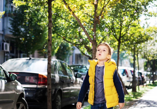 istock Little boy blowing soap bubbles on the street. 1298162364