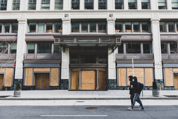 Washington DC, USA - January 20, 2021: Two pedestrians walk past a boarded up building, the Homer Building, on 13th St NW in downtown Washington DC.