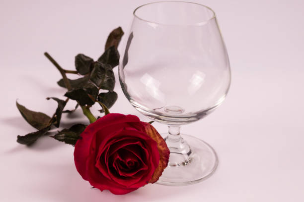 istock white transparent glass and pink rose next to it 1298164902