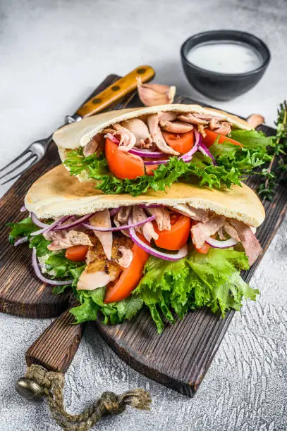 Pita sandwich with roasted chicken, vegetables and delicious sauce. White background. Top view.