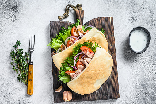 Pita sandwich with roasted chicken, vegetables and delicious sauce. White background. Top view.