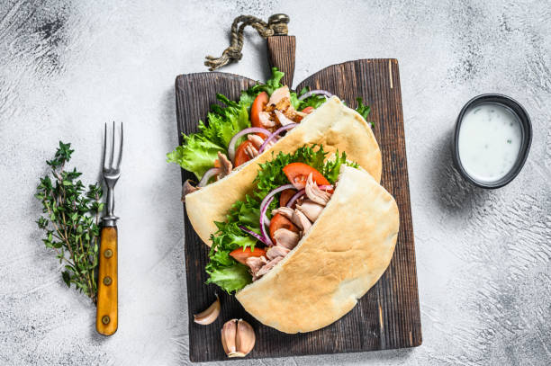 Pita sandwich with roasted chicken, vegetables and delicious sauce. White background. Top view Pita sandwich with roasted chicken, vegetables and delicious sauce. White background. Top view. pita bread stock pictures, royalty-free photos & images