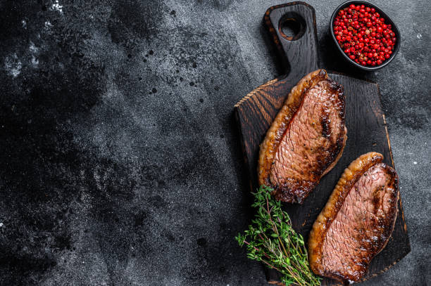 bbq grilled top sirloin cap or picanha steak on a wooden cutting board. black background. top view. copy space - picanha beef meat rare imagens e fotografias de stock