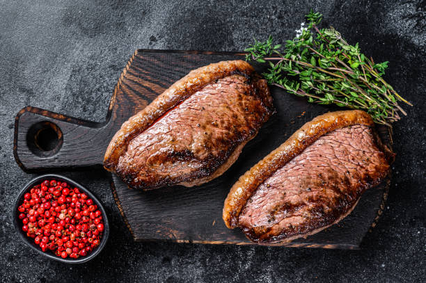 bbq grilled top sirloin cap or picanha steak on a wooden cutting board. black background. top view - picanha beef meat rare imagens e fotografias de stock