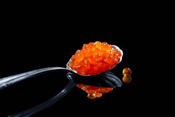 istock Red caviar in the spoon on black background with reflection 1298167271