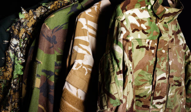 istock Hanging military camouflaged jackets on black background. 1298167335