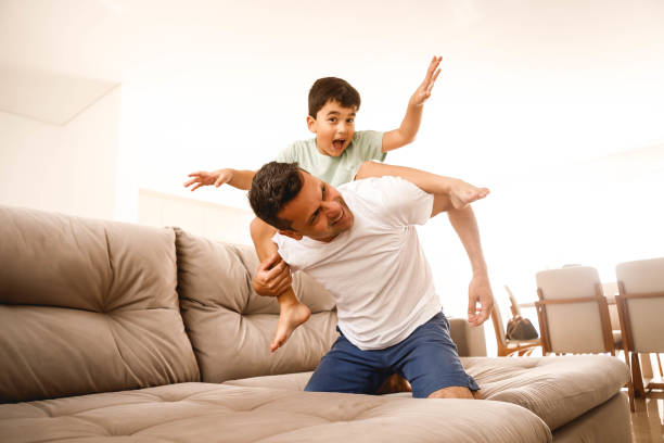 istock father playing with his son in the home room 1298167394