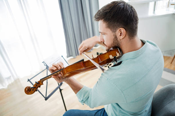 istock Young Caucasian man playing violin at home 1298167596