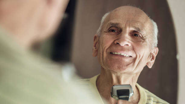 istock Cheerful active elderly man shaving his chin with electrical shaver 1298168497