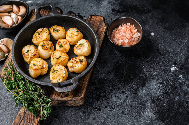istock Fried scallops with butter sauce in a pan. Black background. Top view. Copy space 1298169727