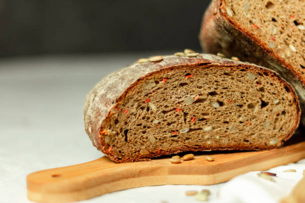 istock Black sliced bread on a wooden board with a knife against a white background. Blurred background. Copy space 1298170231