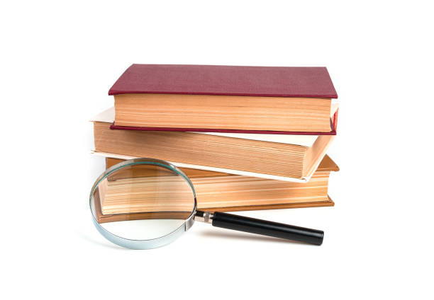 istock Stack of books, textbooks with magnifying glass isolated on white background 1298171657