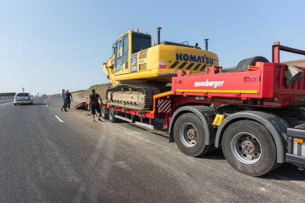 Russia, Krasnodar, European route E-97: September 17, 2020-Workers load a Komatsu Limited crawler excavator on a Meusburger transporter-trailer equipment for mainline and special transportation