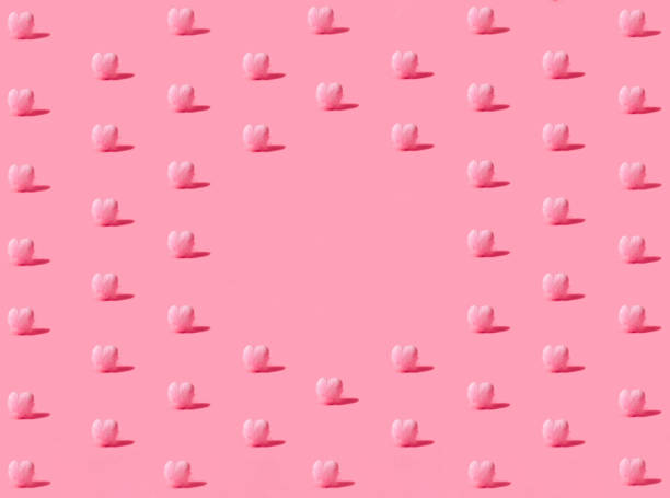 istock Isometric pattern created of small hearts covered with feathers in pink color. Copy space in the middle. 45 degree angle on pastel pink background. 1298172703