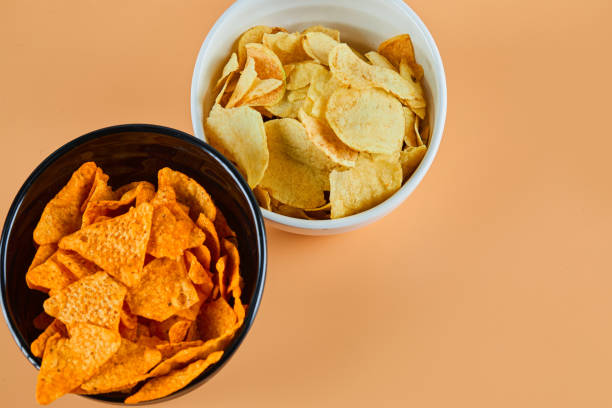 istock Two bowls of chips on orange background 1298173161