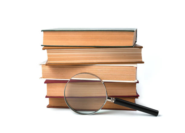 istock A stack of books and a magnifying glass on a white background 1298175437