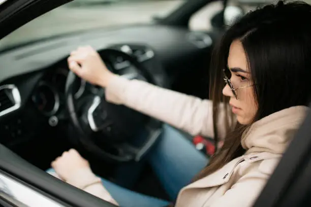 Photo of Side view of a beautiful young Caucasian woman driving a car