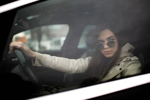 Photo of Side view of a beautiful young Caucasian woman driving a car
